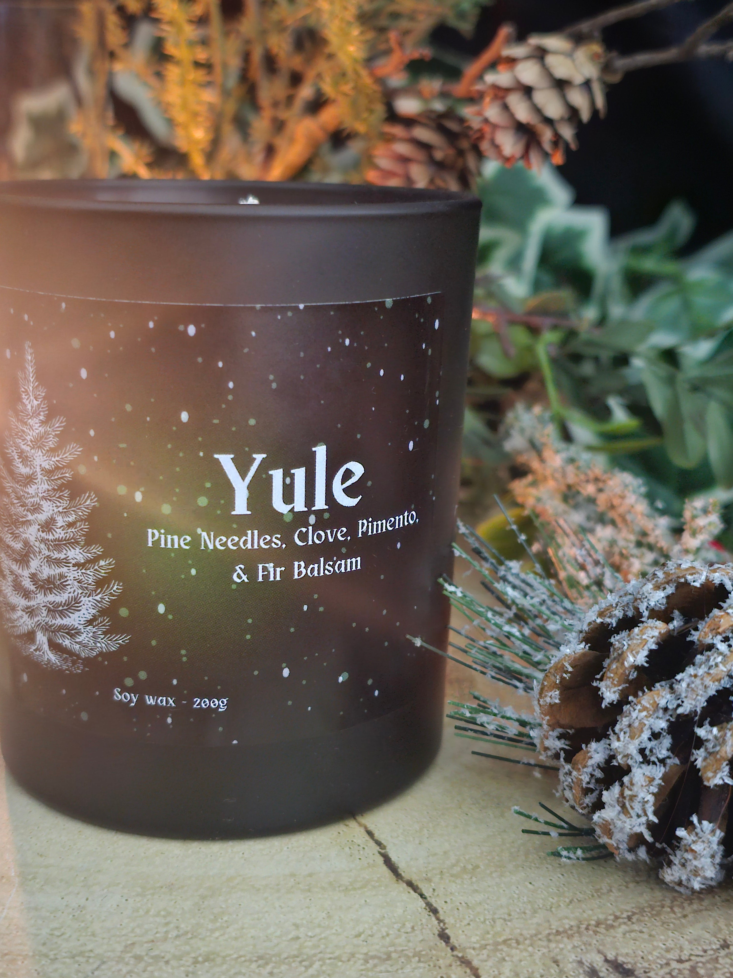 Candle labeled 'Yule' with decorative elements on a natural background