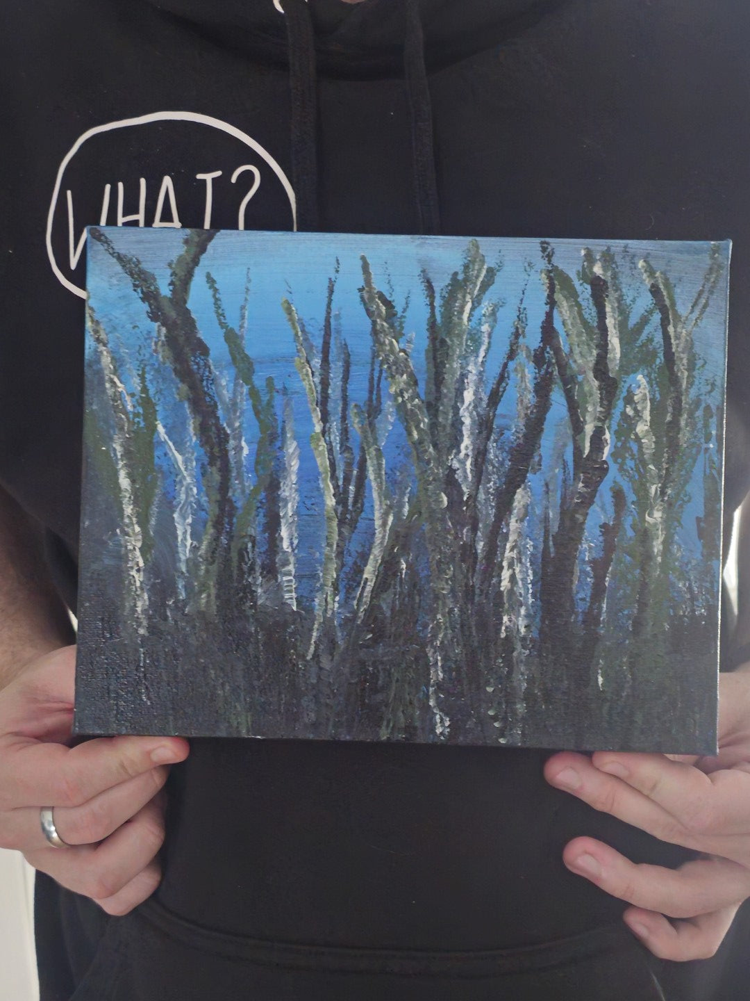 Person holding a small abstract painting with blue and black brush strokes.
