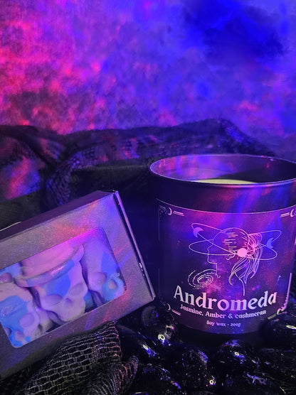 Candle labeled 'Andromeda' with decorative packaging on a dark background