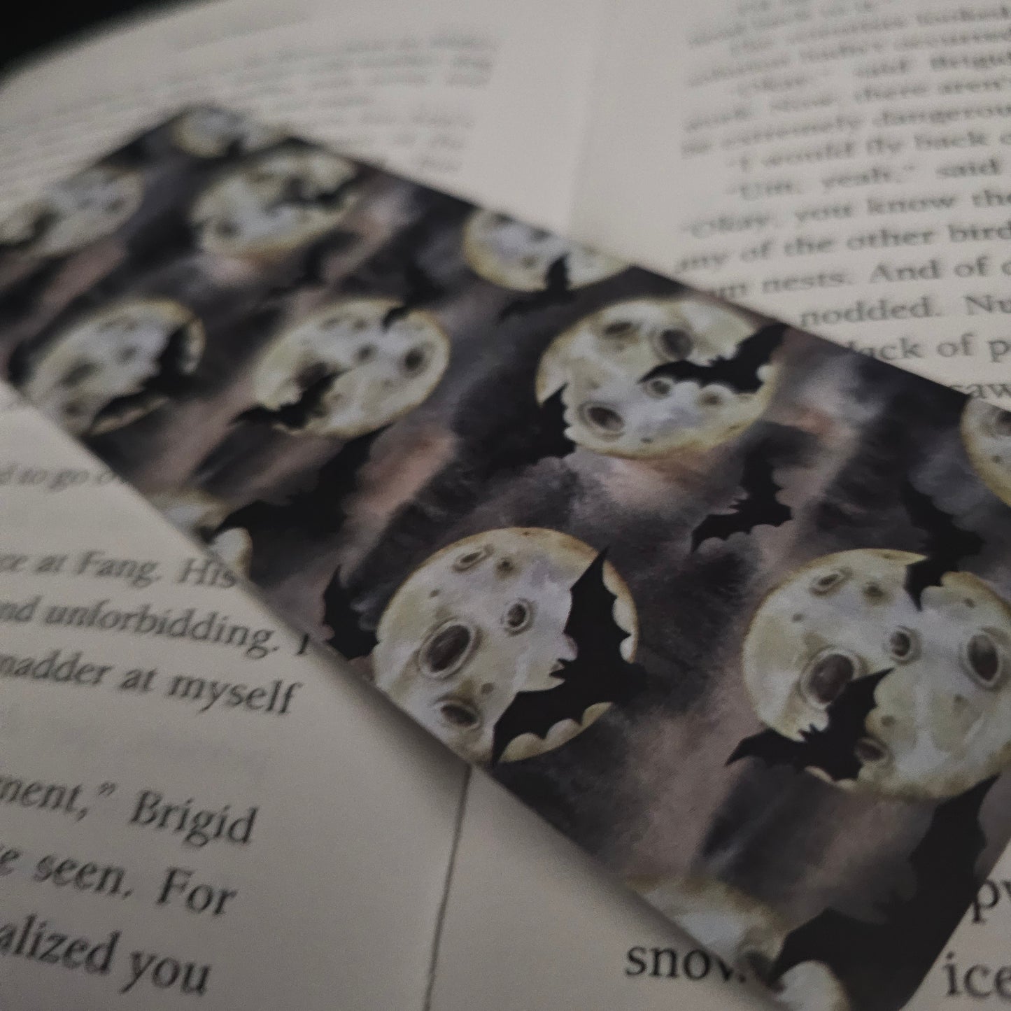 A bookmark decorated with bats and full moons, placed on an open book