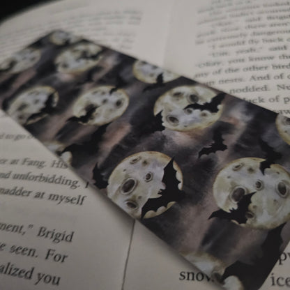 A bookmark decorated with bats and full moons, placed on an open book