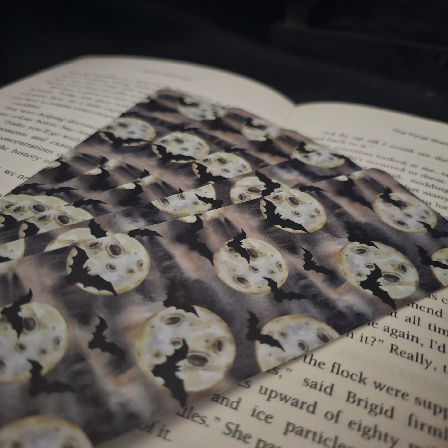 A pile of bookmarks with a bat and moon repeting pattern laying on an open book 