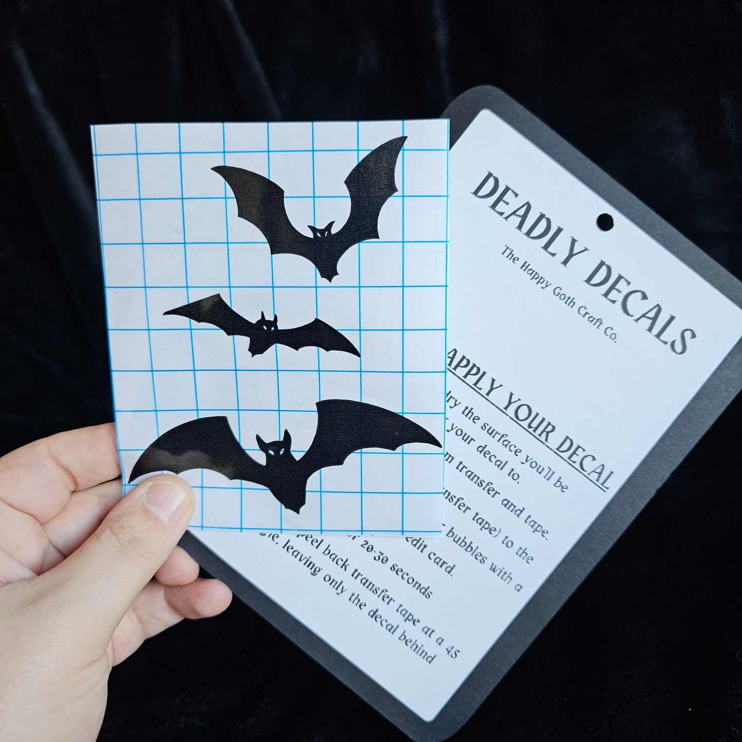 A had holding a not yet applied decal and aplication instructions, against a black background 
