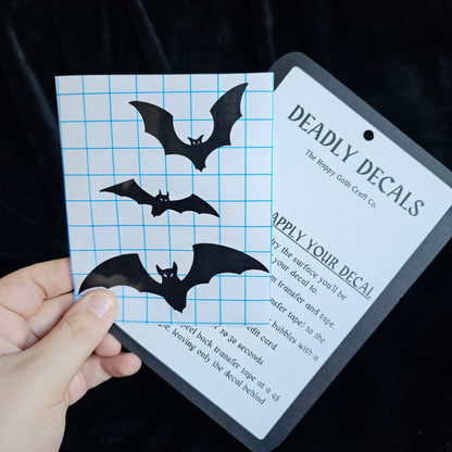 A had holding a not yet applied decal and aplication instructions, against a black background 