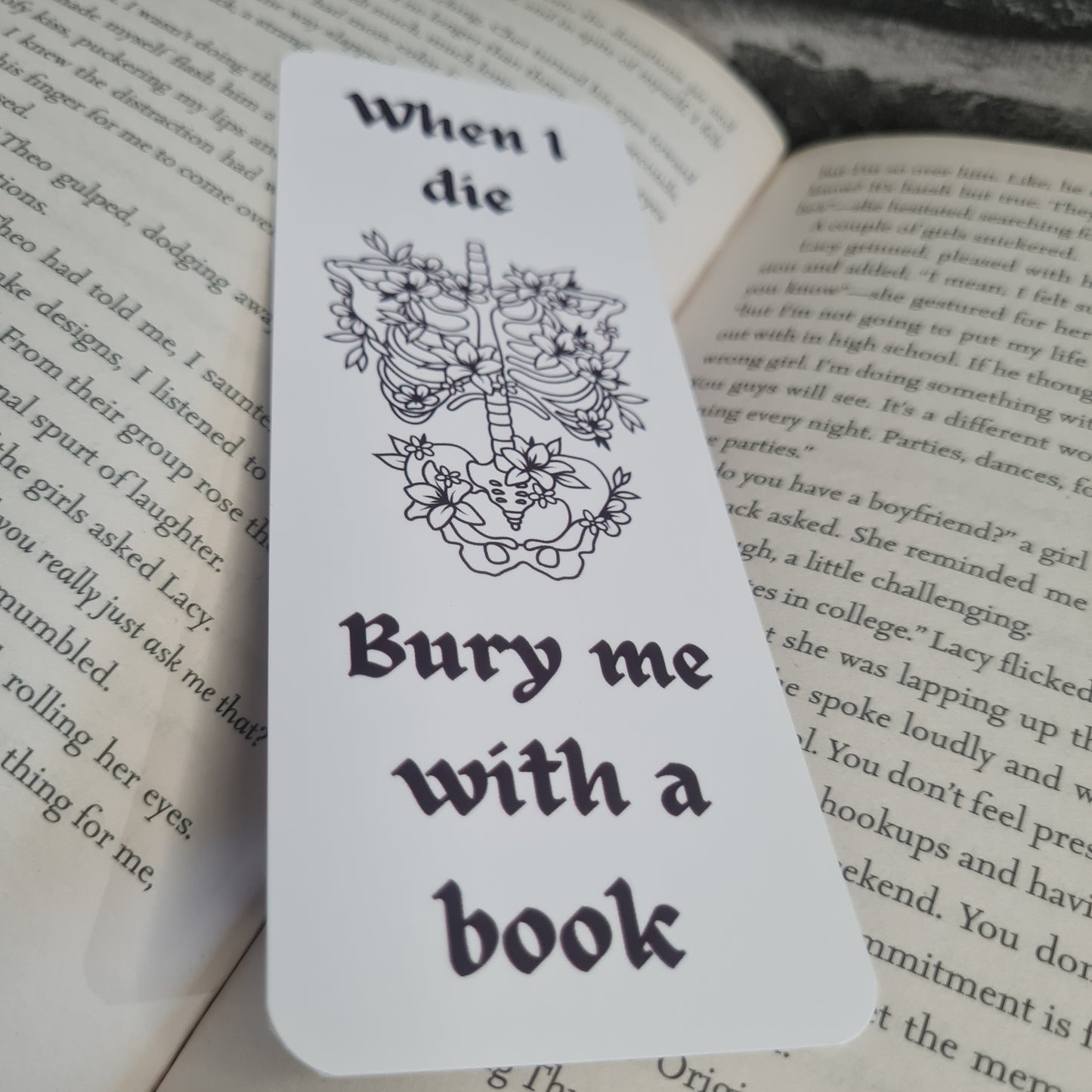 Bookmark with skeleton and floral design, text 'When I die, bury me with a book', on an open book 