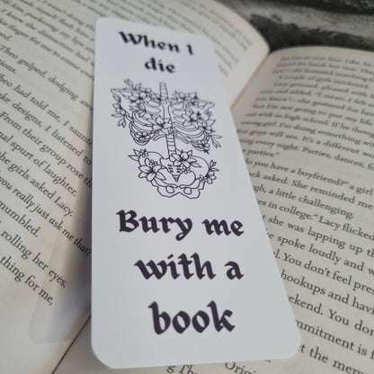 Bookmark with skeleton and floral design, text 'When I die, bury me with a book', on an open book 
