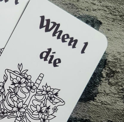 Bookmark with skeleton and floral design, text 'When I die, bury me with a book', held against a stonework background 