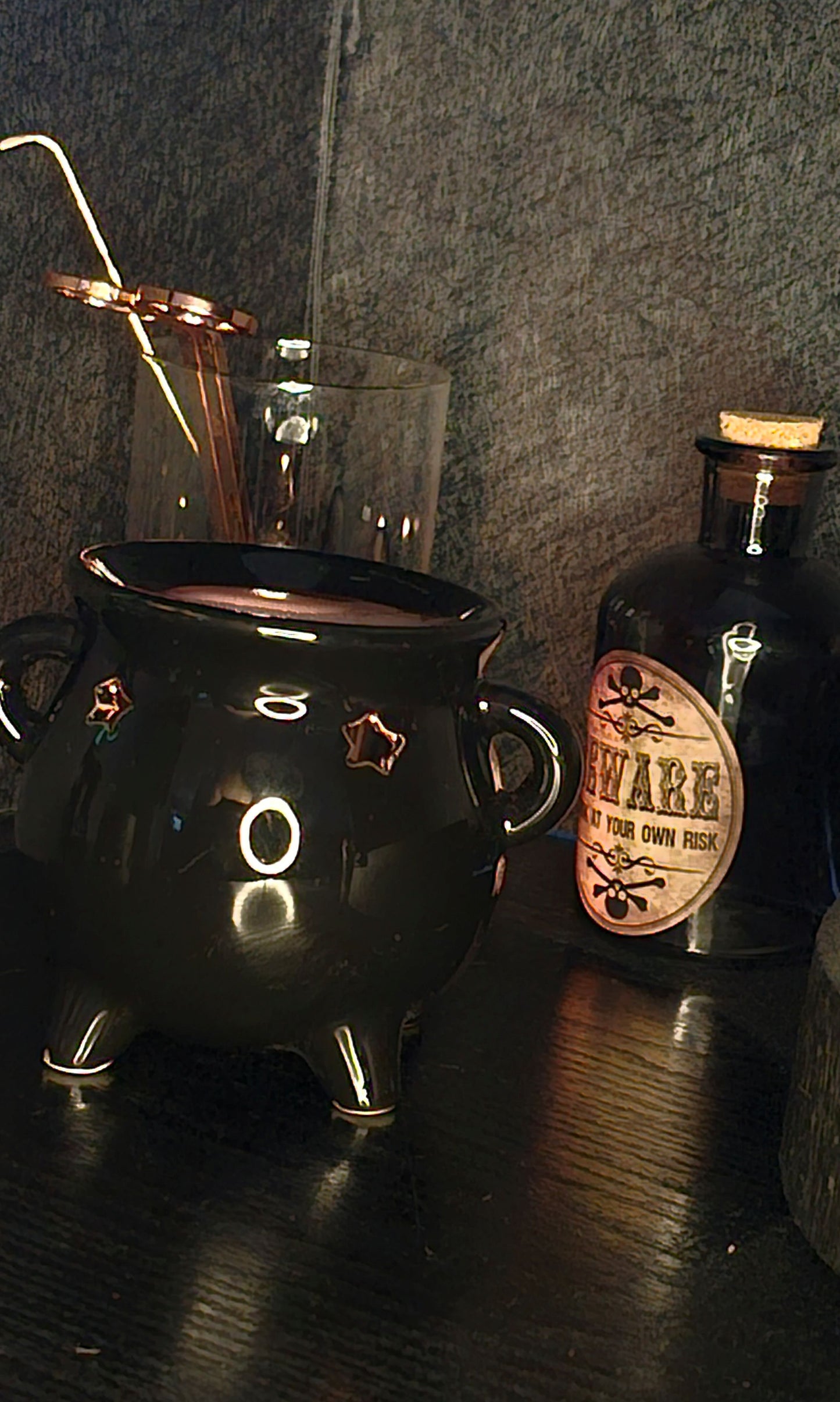 Black cauldron with a bottle labeled 'BEWARE' on a dark surface
