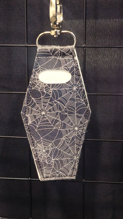 Coffin-shaped lip gloss holder keychain in black spiderweb print leatherette with stainless steel lobster clasp.