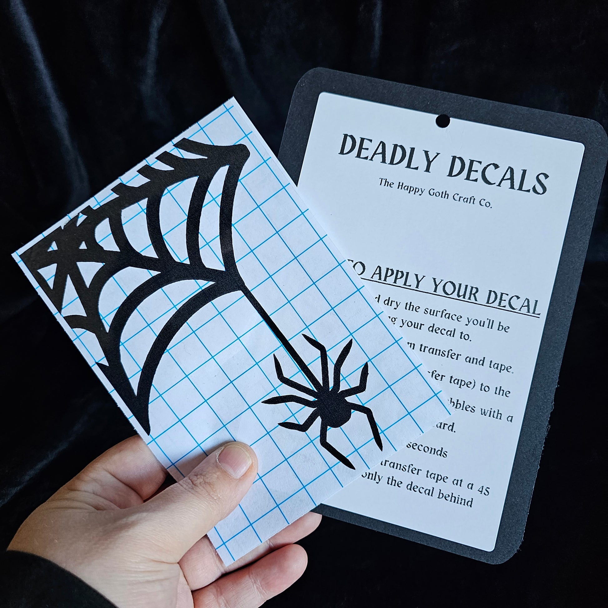 A had holding a not yet applied decal and aplication instructions, against a black background 