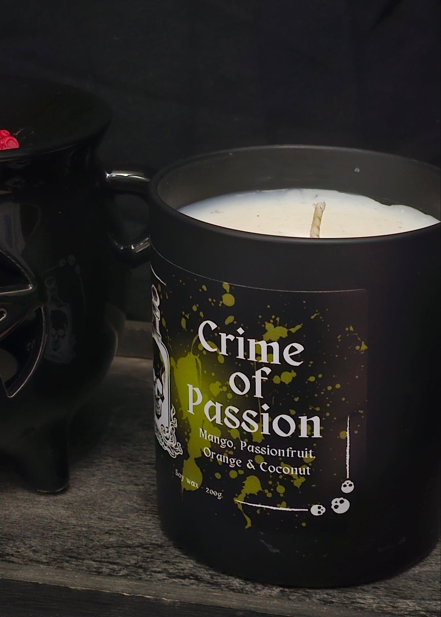 A candle housed in a black jar labelled "Crime of Passion; mango, passionfruit, Orange & Coconut"