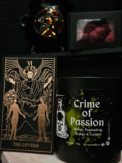 Candle labeled 'Crime of Passion' sitting on a marble surface, in the background a pentagram shaped wax burner and melts, and "the lovers" tarot card 