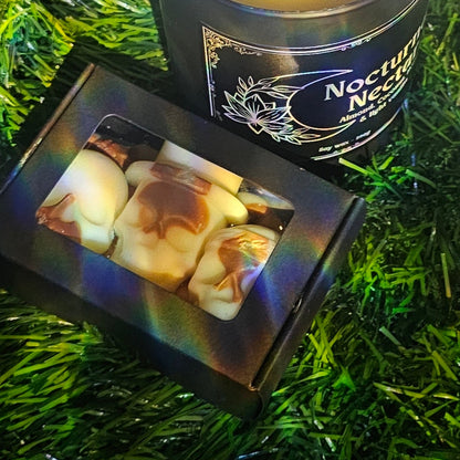 Box of skull shaped wax melts with Nocturnal Nectar Happy Goth Craft Co branded candle on a grassy background