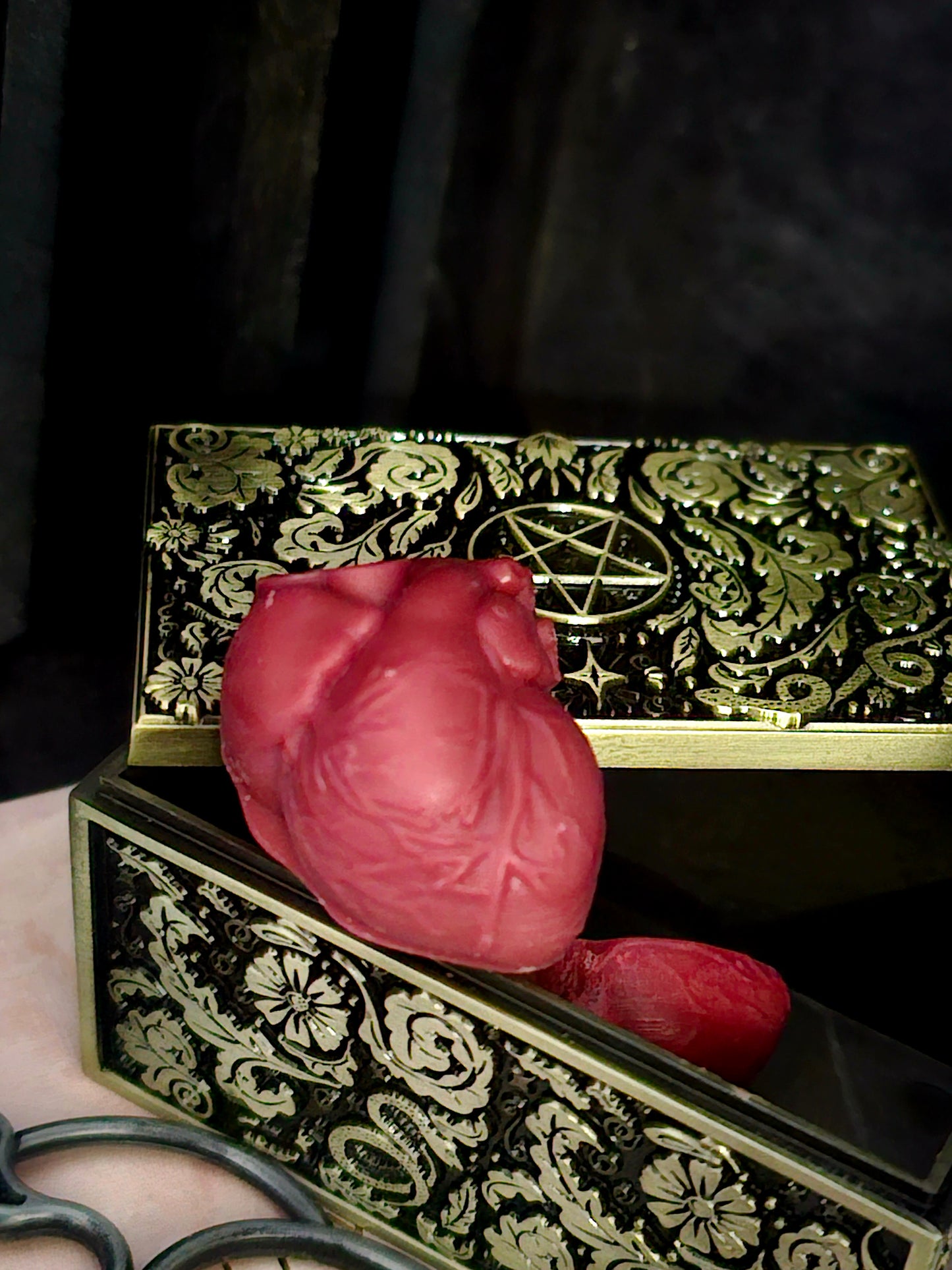 Decorative box with intricate designs and a red heart-shaped object on a dark background