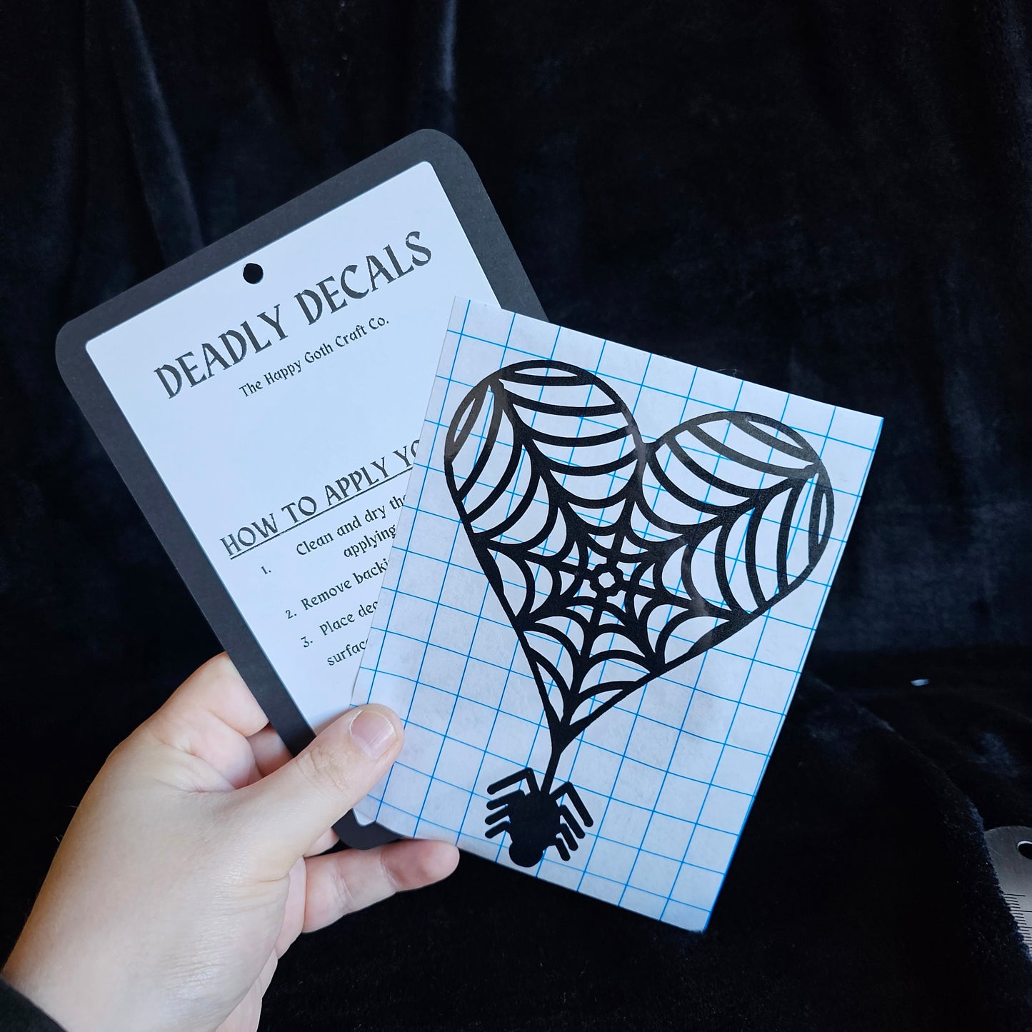 A had holding a not yet applied decal and aplication instructions, against a black background 