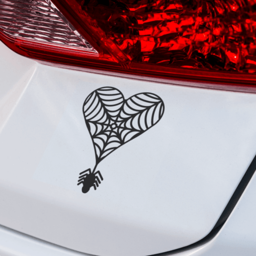 A vinyl decal of a heart-shaped spider web design on the rear of a vehicle.