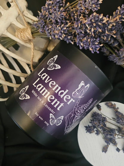 Candle labeled 'Lavender Lament' with lavender flowers around it