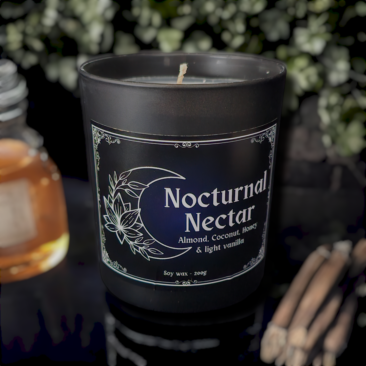 A black glass candle container with a white bamboo lid, labeled 'Nocturnal Nectar', with illustrations of a moon and flowers.