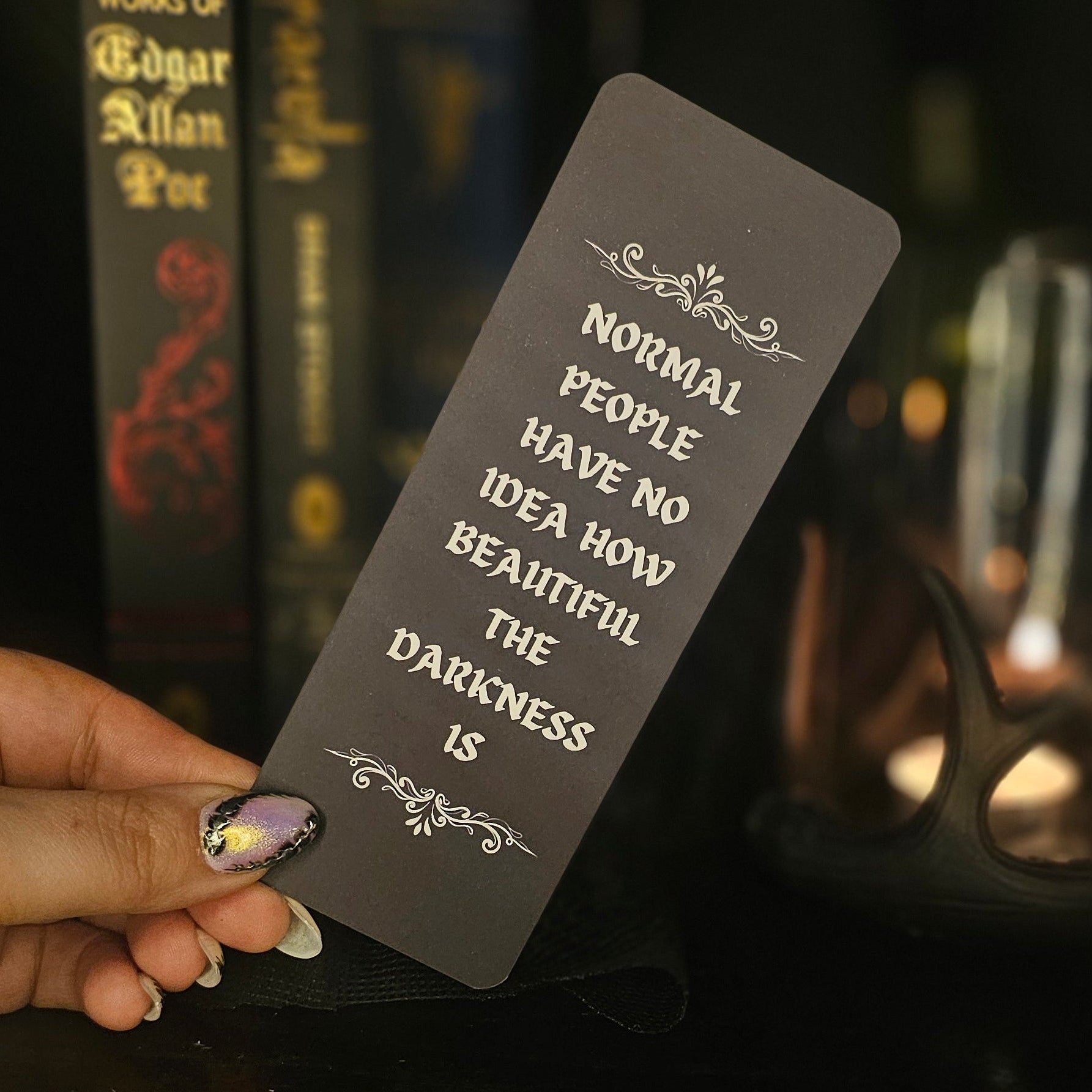 Bookmark with text held by a hand in front of books