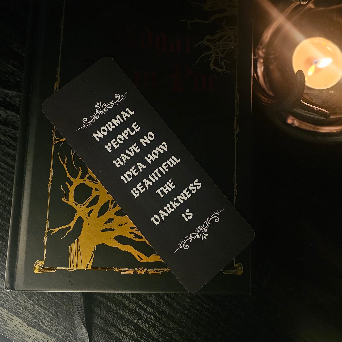 Black bookmark laying on the front cover of a black and gold book. 