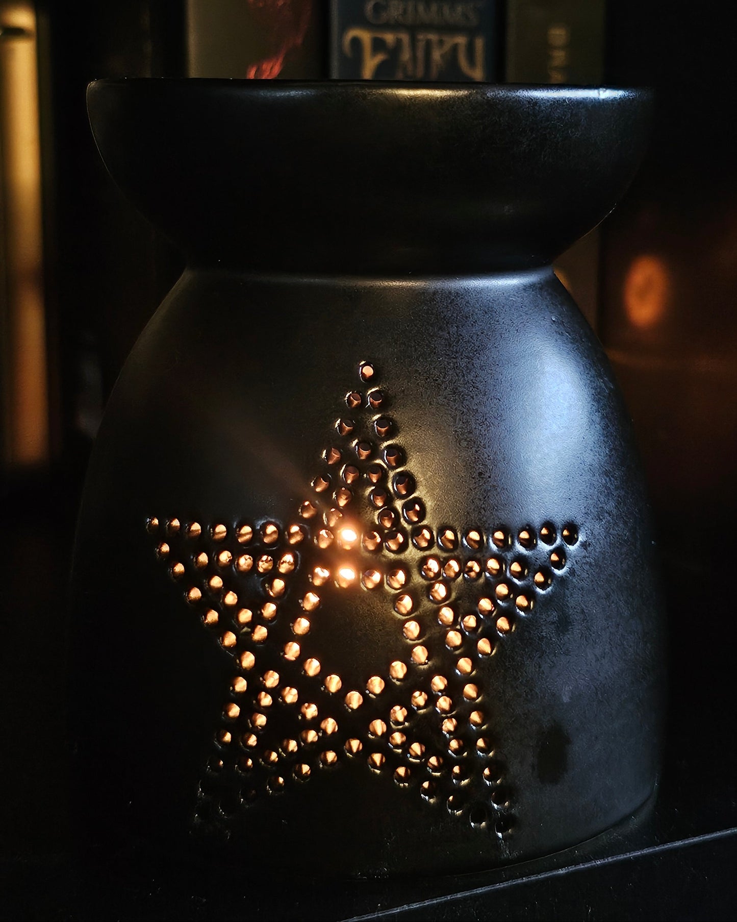 Black ceramic oil burner with star / pentagram design on a dark background 