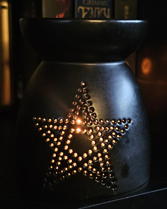 Black ceramic oil burner with star / pentagram design on a dark background 