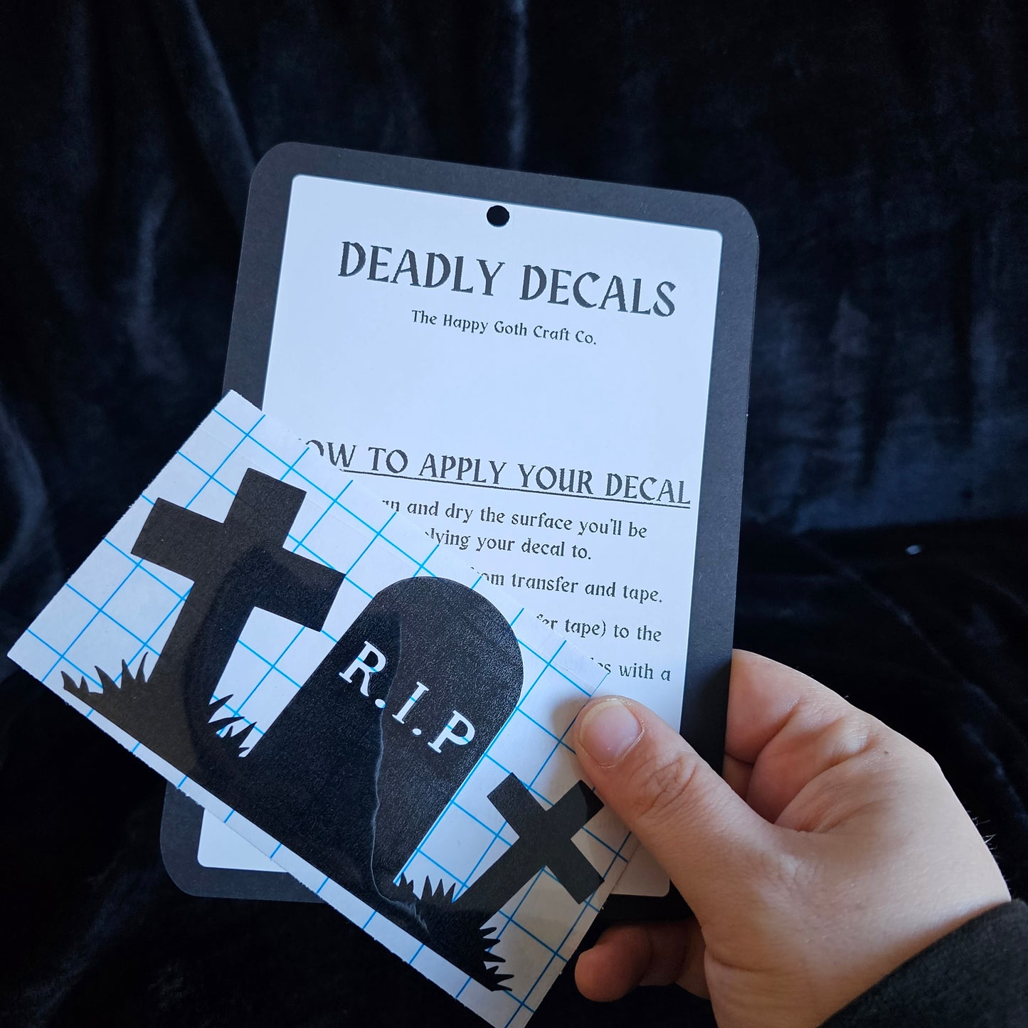 A had holding a not yet applied decal and aplication instructions, against a black background 
