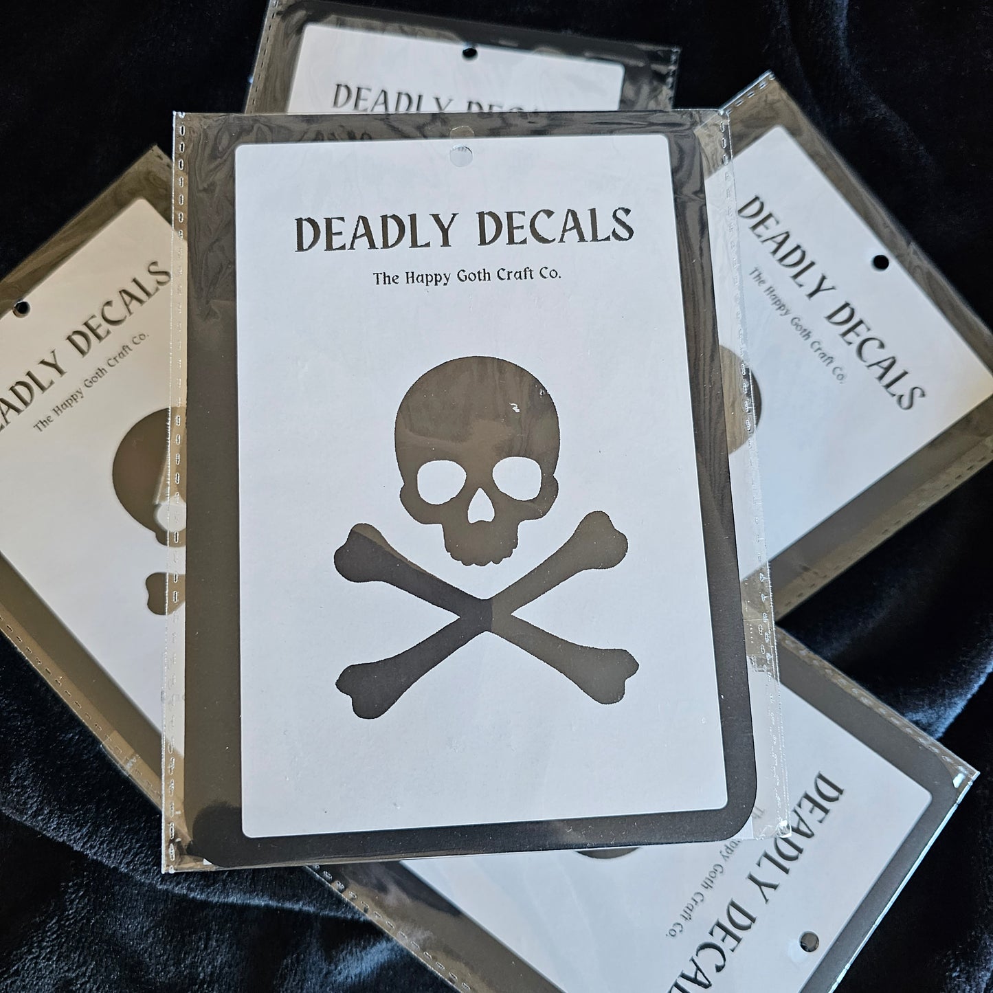 A decal still in its packaging displayed on top of a pile of other decals against  a black backdrop 
