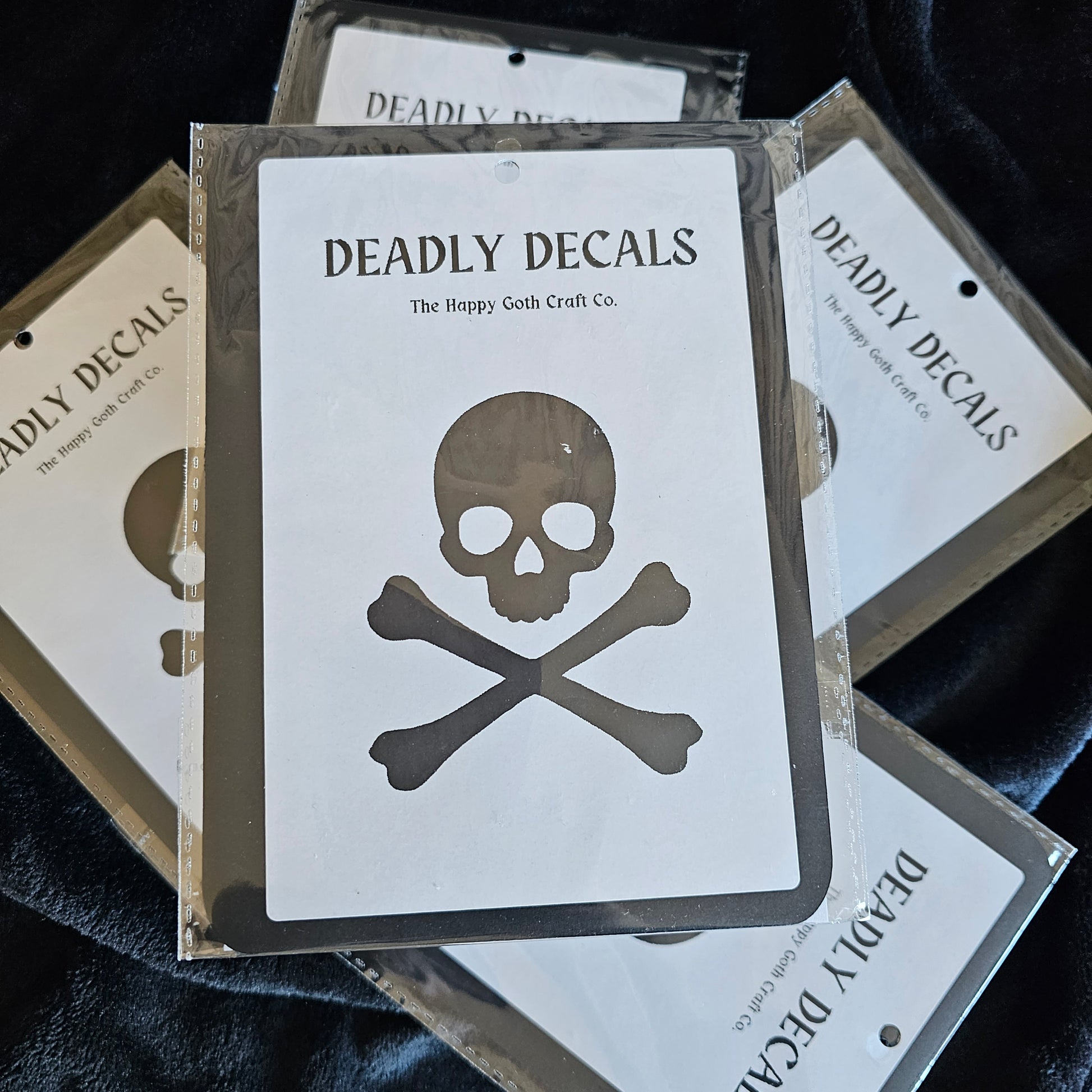 A decal still in its packaging displayed on top of a pile of other decals against  a black backdrop 