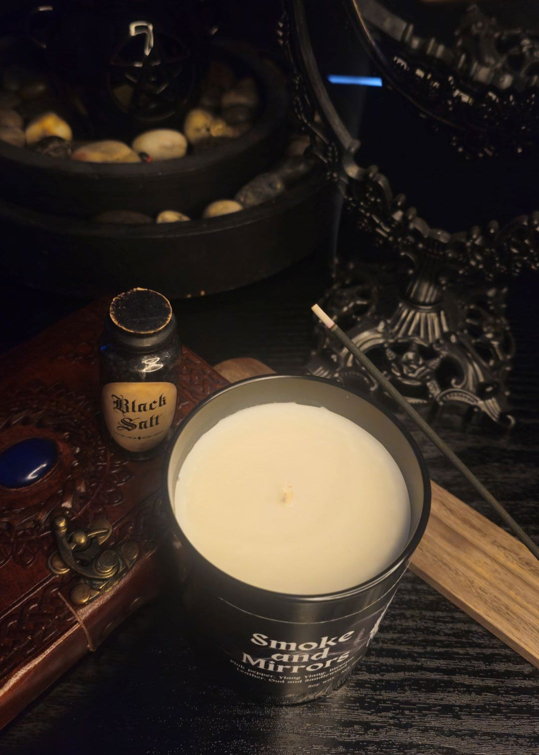 Candle and bottle on a dark surface with decorative dark acedemia elements