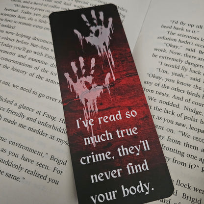A bookmark with a blood-red background featuring handprint illustrations and the text 'I've read so much true crime, they'll never find your body.'.