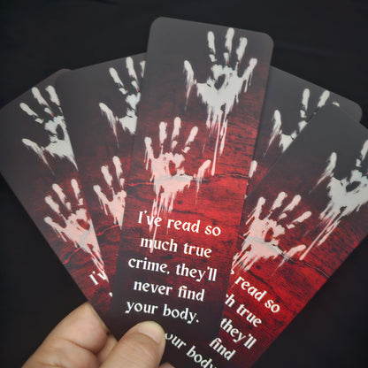 A bookmark with a blood-red background featuring handprint illustrations and the text 'I've read so much true crime, they'll never find your body.'.