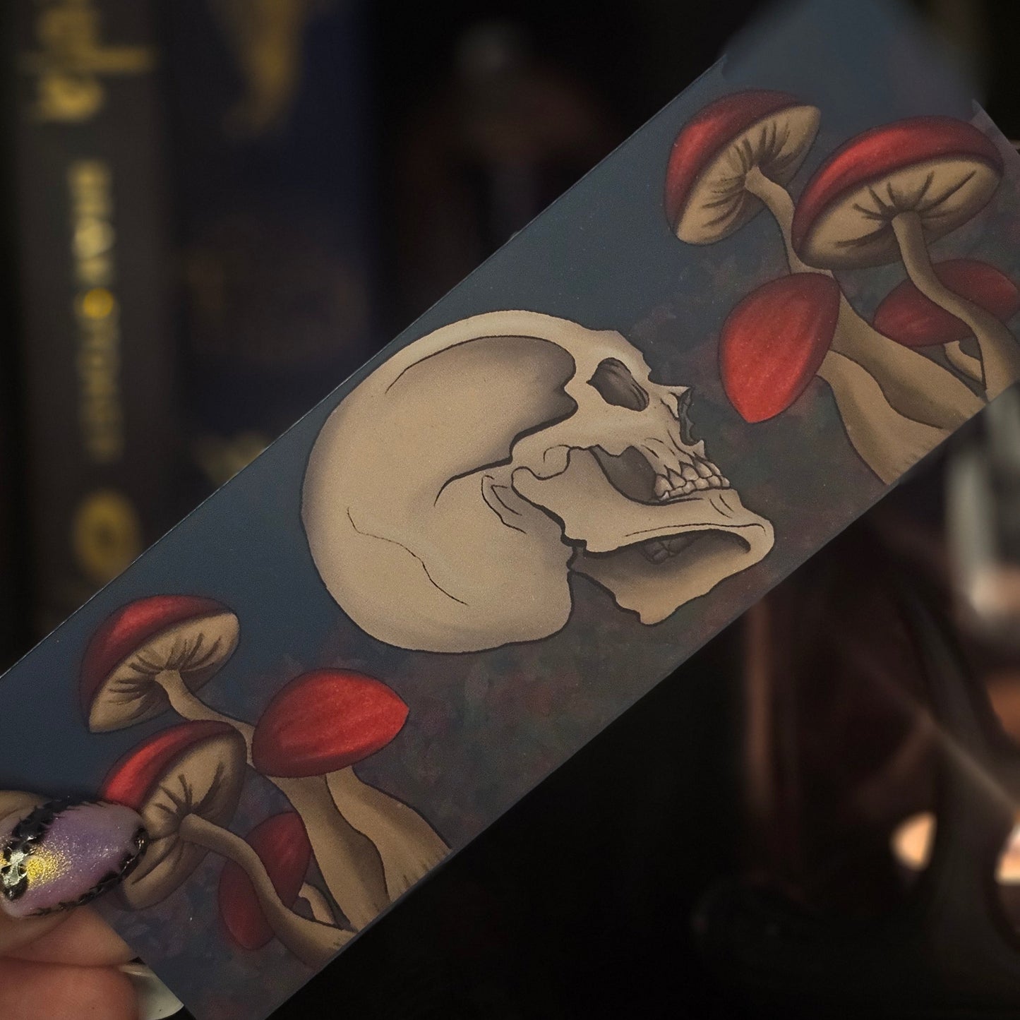 bookmark design with skull and red mushrooms on a dark background